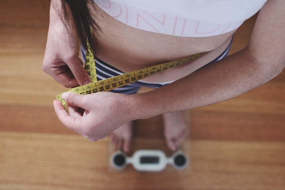Woman standing on scale - avoiding top weight loss mistakes