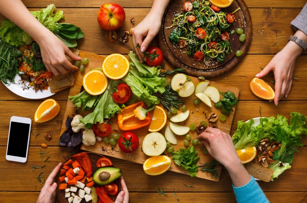 Friends gathered around a table full of healthy foods and vegetables